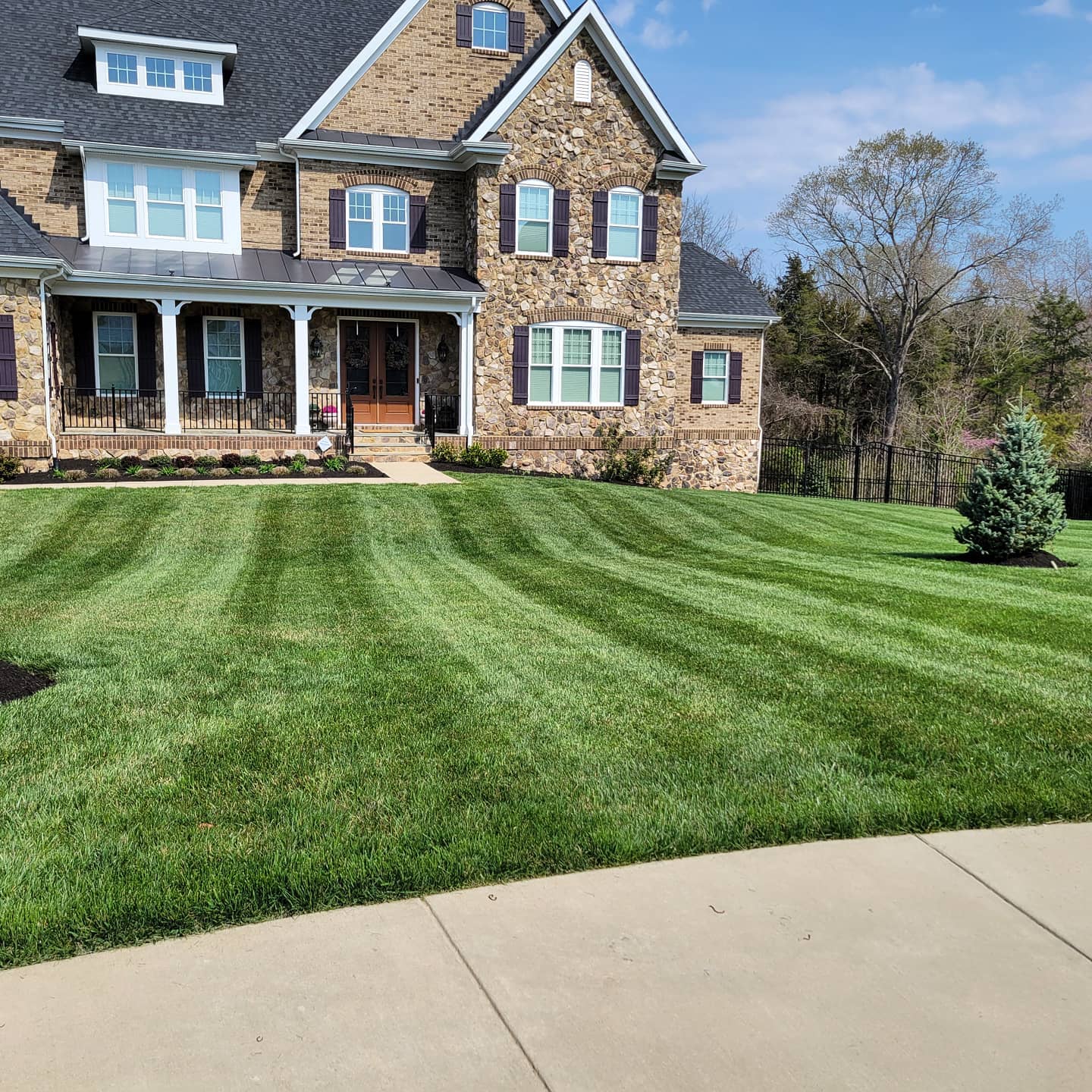 Stone front home with a thick, green front lawn
